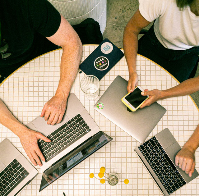 Decorative image, two people sat at a table with laptops